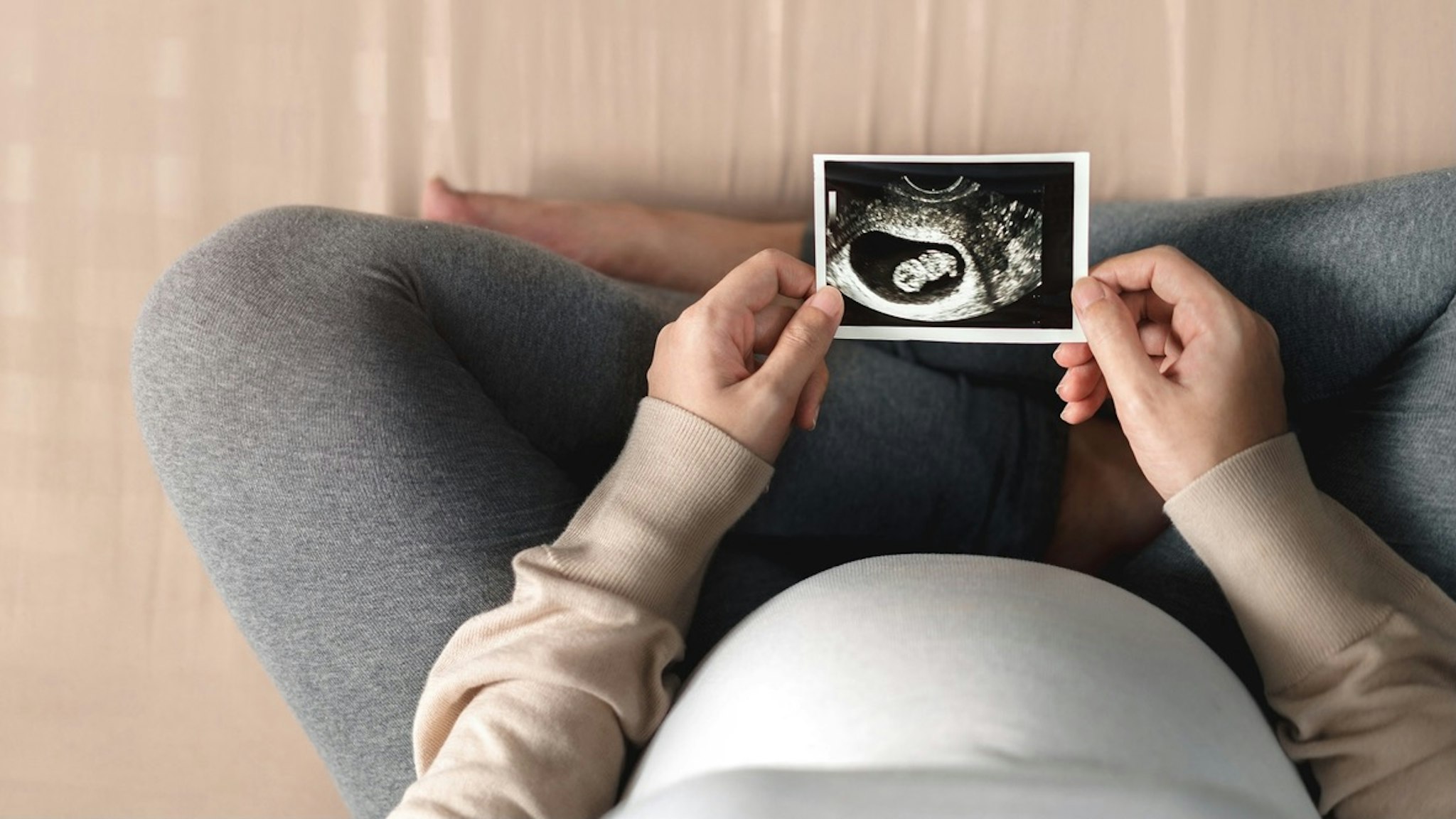 Low Section Of Pregnant Woman Holding Ultrasound Image - stock photo Chanintorn Vanichsawangphan / EyeEm via Getty Images