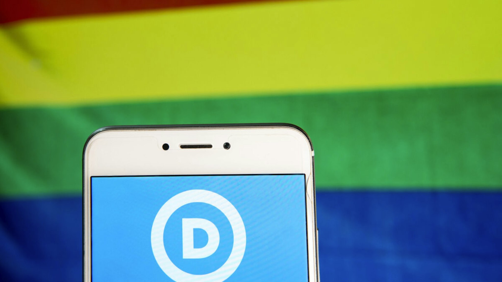 In this photo illustration, the American liberal, progressive and left-wing democratic Party icon is seen displayed on an Android mobile device with a LGTB rainbow in the background