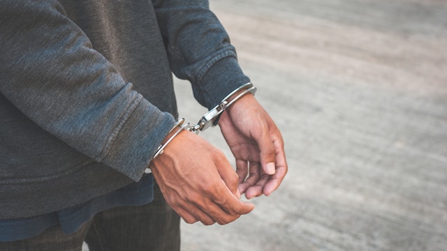 Arrested businessman handcuffed hands. Close-up. - stock photo
