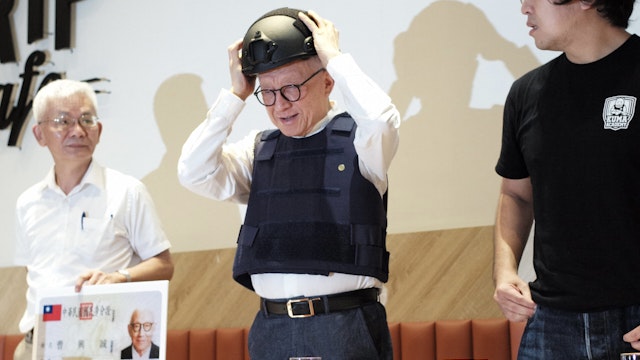 Robert Tsao (C), founder of Taiwanese microchip maker United Microelectronics Corporation (UMC), puts on a tactical helmet while wearing body armour during a press conference at the Parliament in Taipei on September 1, 2022. - A colourful Taiwanese tycoon unveiled plans September 1 to train more than three million "civilian warriors" to help defend the democratic island in the event of a Chinese invasion, donating 33 million USD of his own money