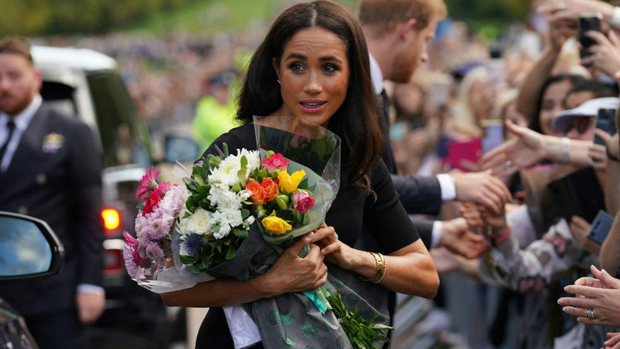 Meghan, Duchess of Sussex collects flowers as she chats with well-wishers on the Long walk at Windsor Castle on September 10, 2022, two days after the death of Britain's Queen Elizabeth II at the age of 96.