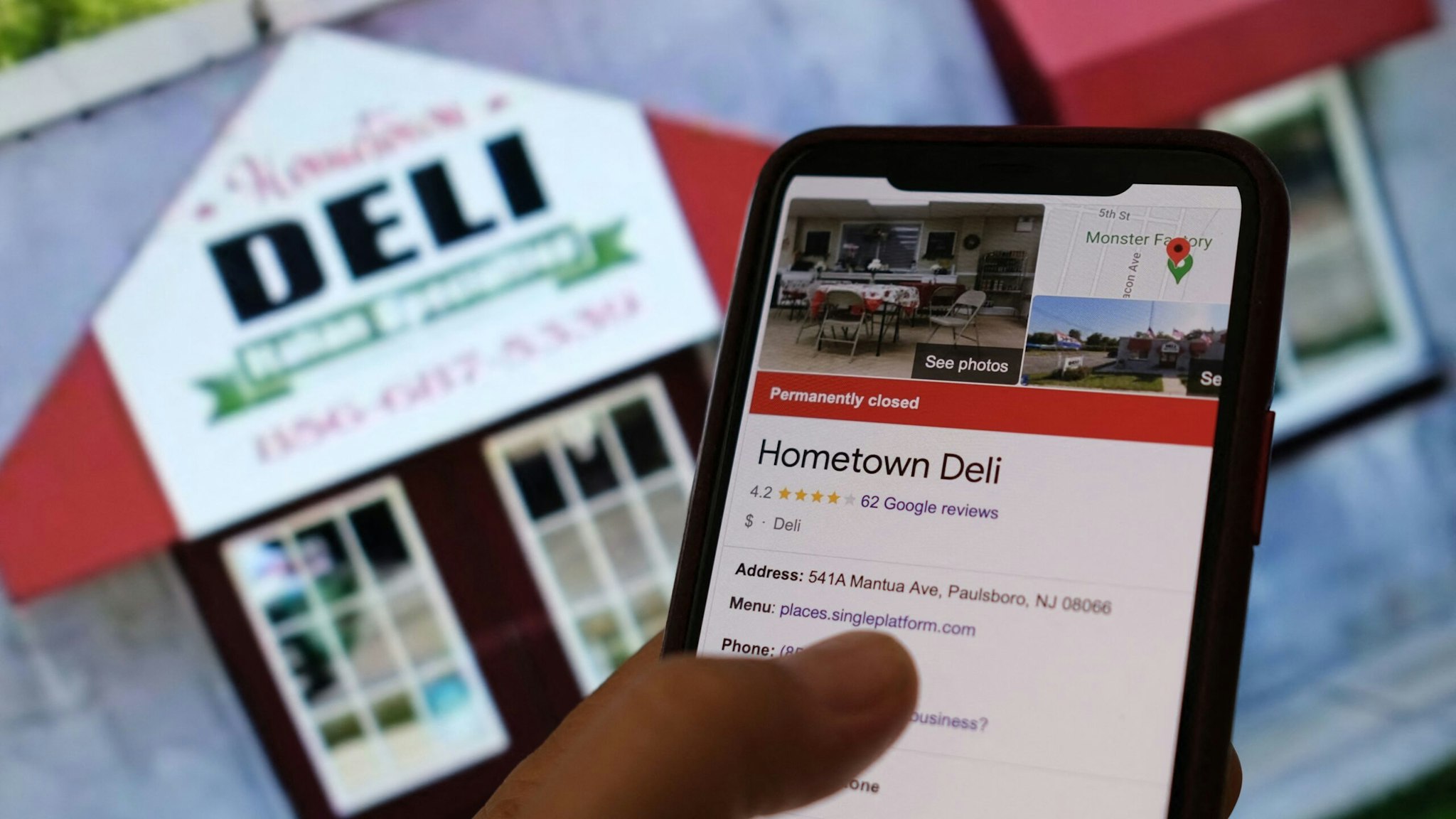 This illustration photo taken on September 26, 2022 in Los Angeles, shows a person checking information online for the now permanently closed Paulsboro, New Jersey's Hometown Deli in front of a screen displaying the facade of the restaurant.