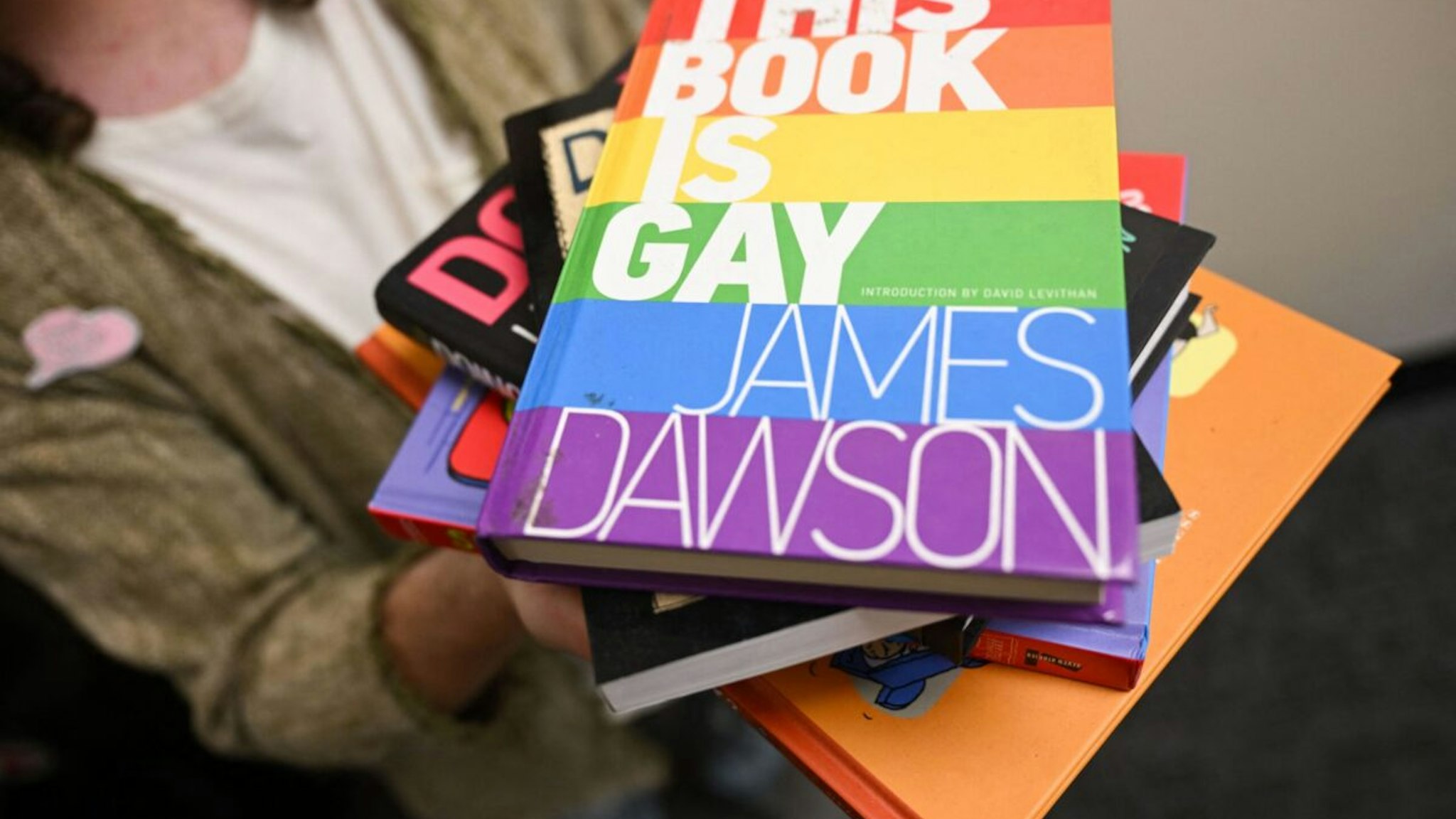 Laramie Pridefest Board Member, Tyler Wolfgang, displays a stack of books, some of which have been banned across the US due to controversy, including "This Book is Gay", in their office on the University of Wyoming campus in Laramie, Wyoming, on August 13, 2022