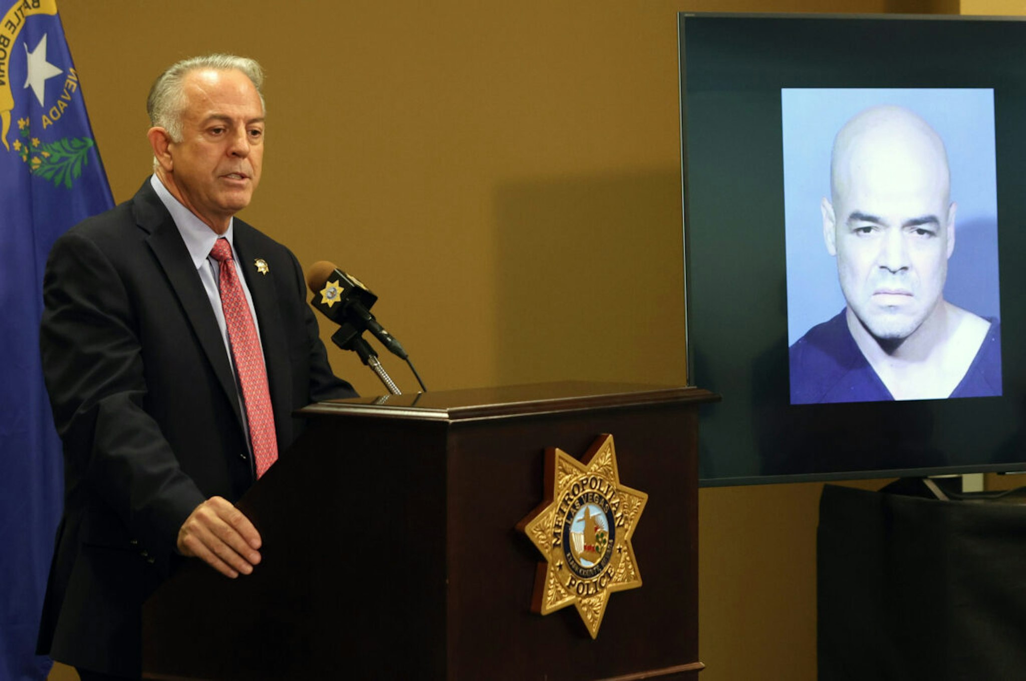 Clark County Sheriff Joe Lombardo speaks at a news conference at the Las Vegas Metropolitan Police Department headquarters to brief media members on the arrest of Clark County Public Administrator Robert Telles, whose booking photo is displayed on a television, on the charge of open murder of Las Vegas Review-Journal investigative reporter Jeff German on September 08, 2022, in Las Vegas, Nevada