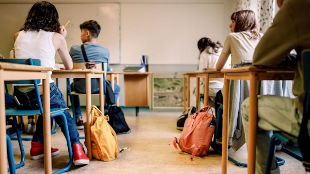 Multiracial group of students sitting at desk in classroom - stock photo