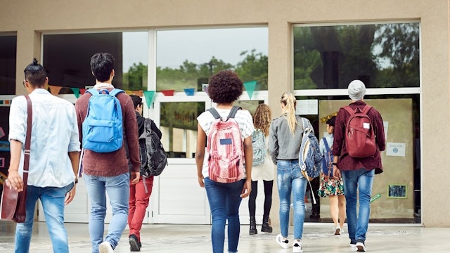 College students walking on campus, rear view - stock photo