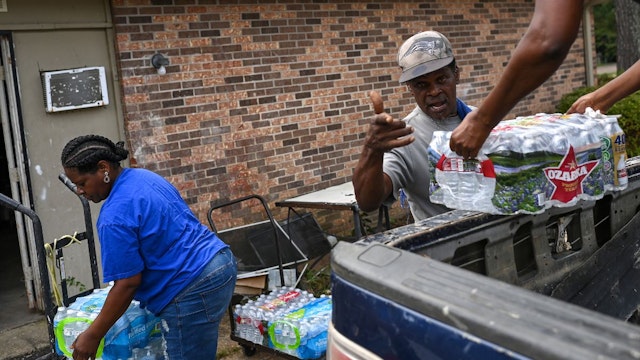 Rodney Moore (C), maintenance supervisor at Addison Place apartments receives cases of bottle water from City of Jackson worker Dianna Davis (R) and Andrea Williams for elderly and disabled residents on September 3, 2022 in Jackson, Mississippi.