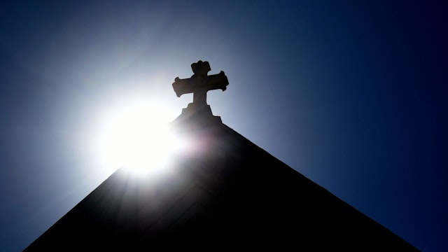 The sun rises behind a stone cross atop the historic Cathedral Basilica of St. Frances of Assisi in Santa Fe, New Mexico.