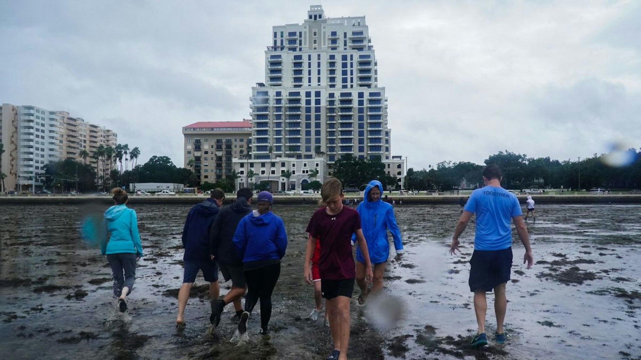 People walk along the mudflats as the tide recedes from Tampa Bay ahead of Hurricane Ian making landfall on September 28, 2022 in Tampa, Florida.