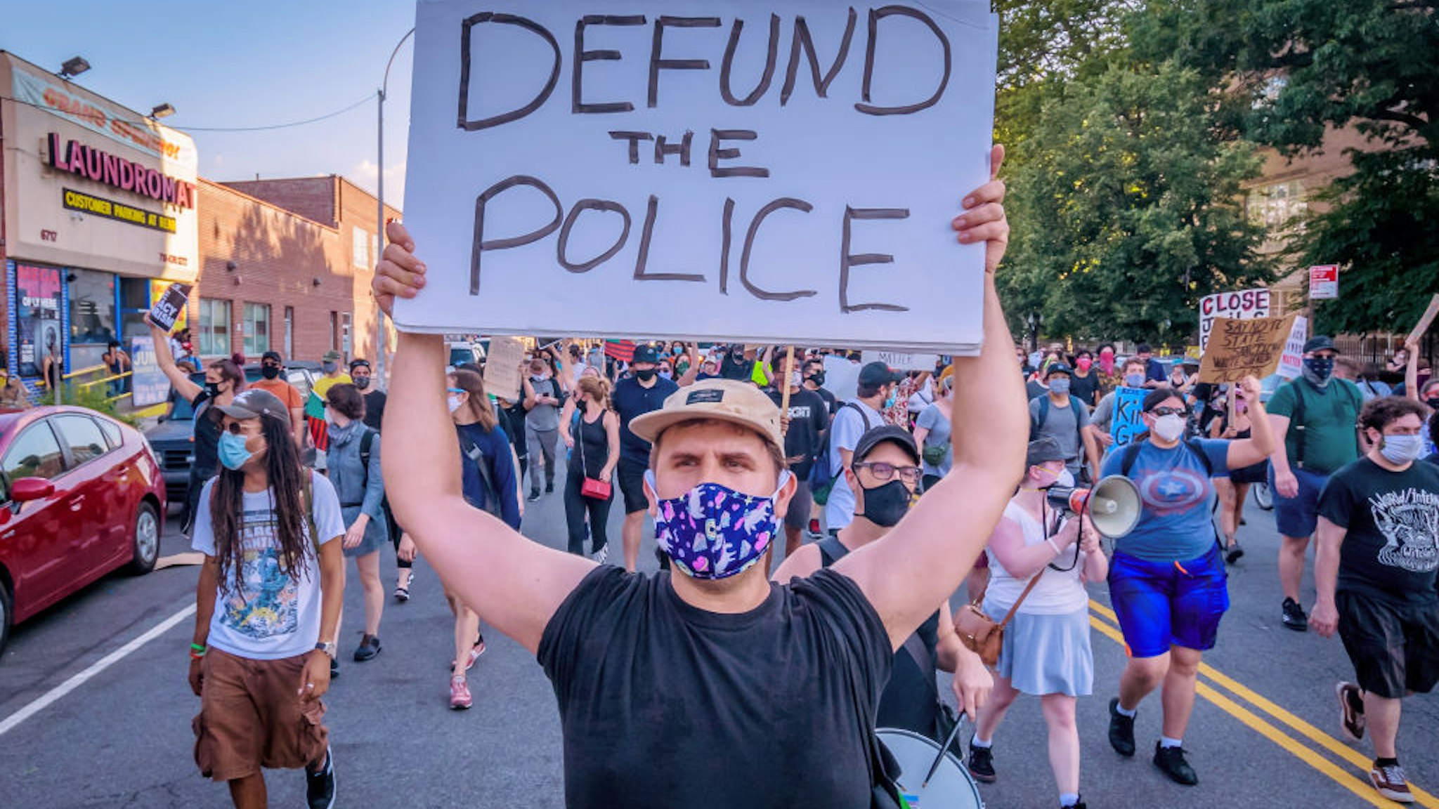 BROOKLYN, NEW YORK, UNITED STATES - 2020/07/12: A counterprotester holding a Defund Police sign at the protest. Pro-NYPD marchers clashed with a big crowd of Black Lives Matter counterprotesters during the Ã¬Back the BlueÃ® rally and march in Bay Ridge, Brooklyn.