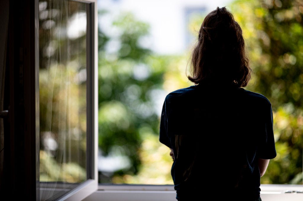 PRODUCTION - 13 July 2021, Berlin: ILLUSTRATION - A woman stands at a window in her apartment. (posed scene - to dpa: "Freedom before the next wave? Why some miss the lockdown") Photo: Fabian Sommer/dpa (Photo by Fabian Sommer/picture alliance via Getty Images)