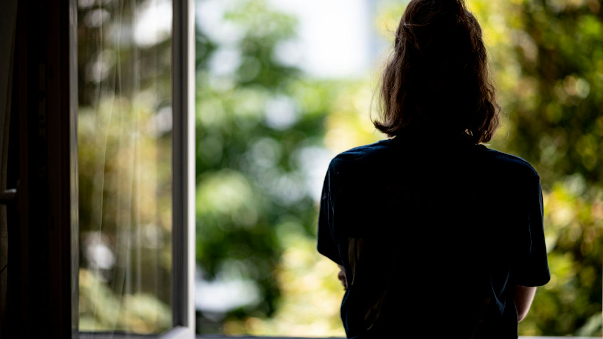 PRODUCTION - 13 July 2021, Berlin: ILLUSTRATION - A woman stands at a window in her apartment. (posed scene - to dpa: "Freedom before the next wave? Why some miss the lockdown") Photo: Fabian Sommer/dpa (Photo by Fabian Sommer/picture alliance via Getty Images)