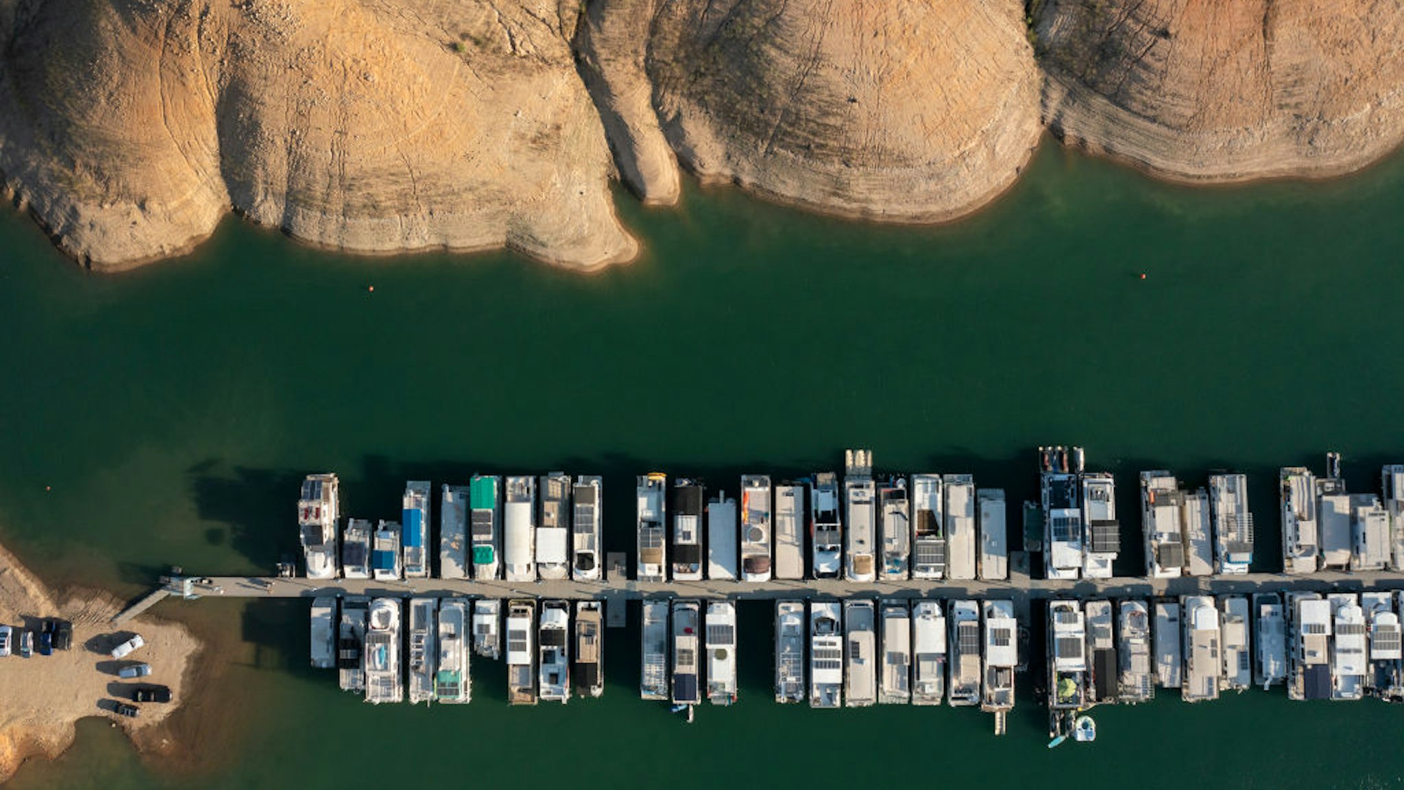 REDDING, CA - AUGUST 5: In an aerial view, boasts are docks near bare ground at drought-stricken Lake Shasta, which is ringed with formerly submerged land, on July 5, 2022 near Redding, California. Scientists are calling today's megadrought the driest 22-year stretch in more than 1,200 years, with major California reservoirs dwindling to a fraction of their capacity and no end in sight to when or if a normal Sierra Nevada Mountains snowpack or winter rains could return to refill them.