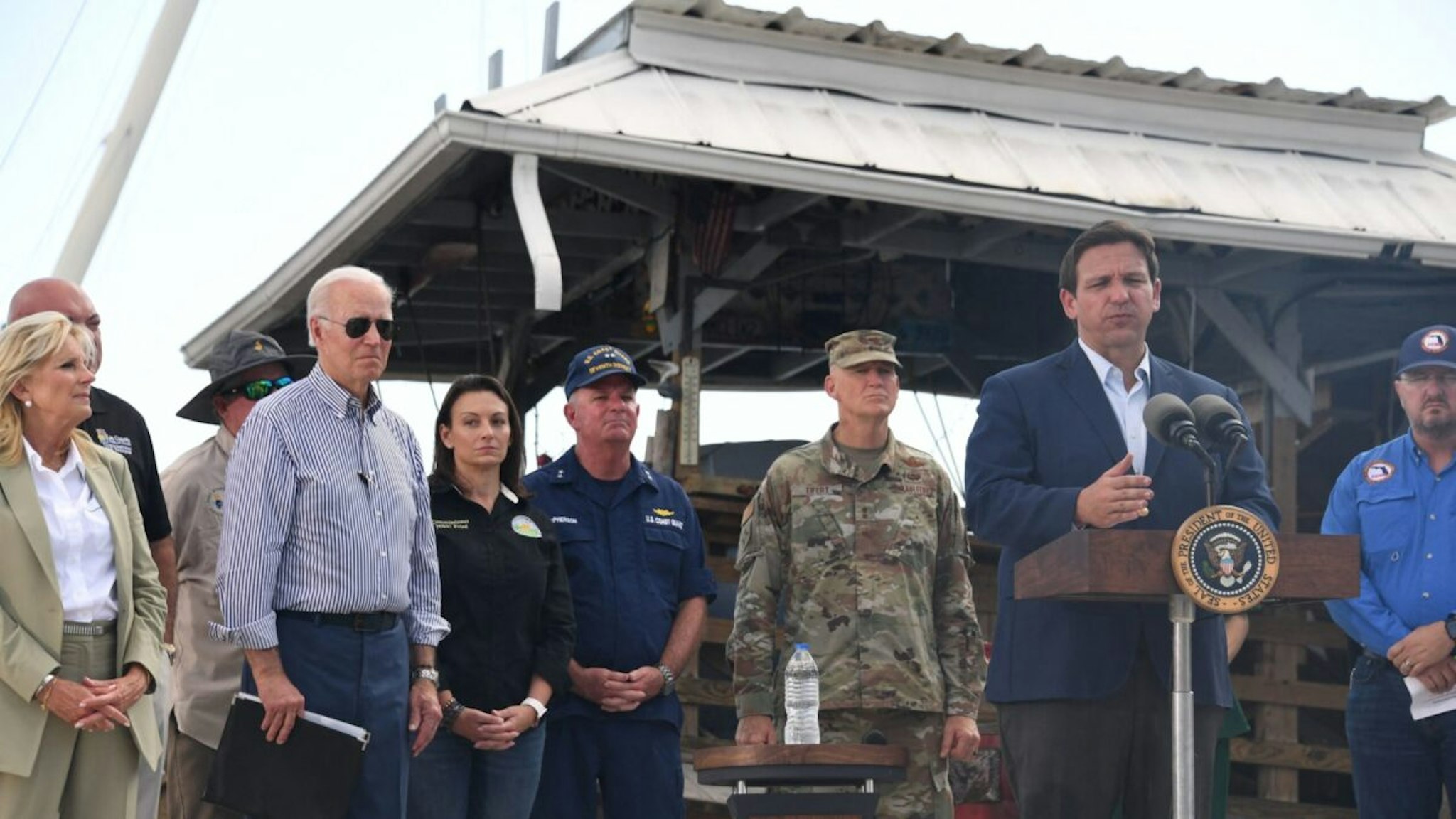 US President Joe Biden and US First Lady Jill Biden listen to Florida Governor Ron DeSantis speak in a neighborhood impacted by Hurricane Ian at Fishermans Wharf in Fort Myers, Florida, on October 5, 2022.
