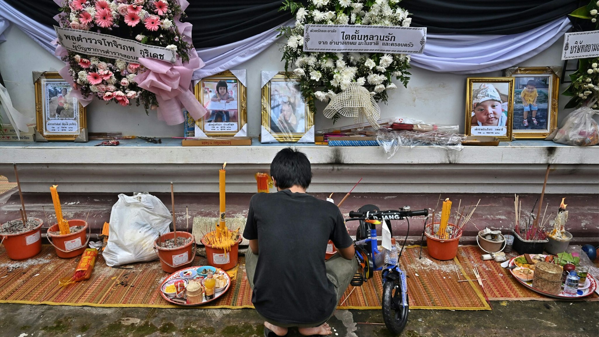 A mourner prays for the victims of the nursery mass shooting at Wat Rat Samakee temple in northeastern Nong Bua Lam Phu province on October 10, 2022, as relatives hold funeral rites for those killed in the massacre. (Photo by Lillian SUWANRUMPHA / AFP)
