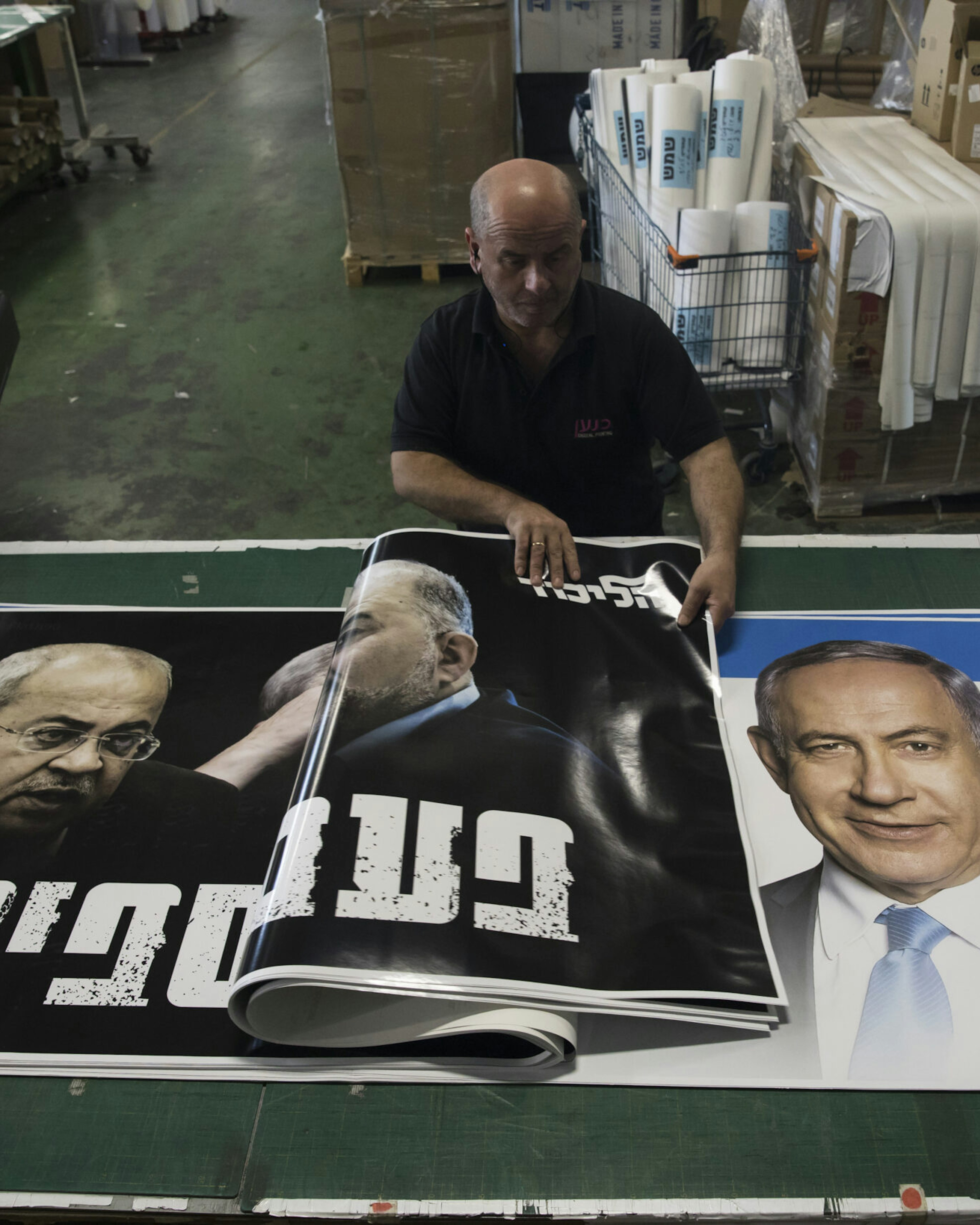 A print house worker rolls up a Likud party election campaign posters that show former Israeli Prime Minister and Likud Party leader Benjamin Netanyahu and member of parliament Ahmad Tibi on October 19, 2022 in Rosh HaAyin, Israel. Legislative elections will be held in Israel on 1 November 2022 to elect the members of the twenty-fifth Knesset.