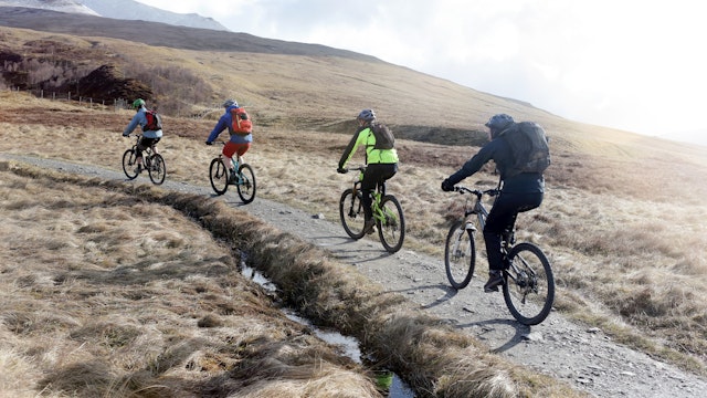 A small group of mountain bikers cycling along a mountain bike trail - stock photo