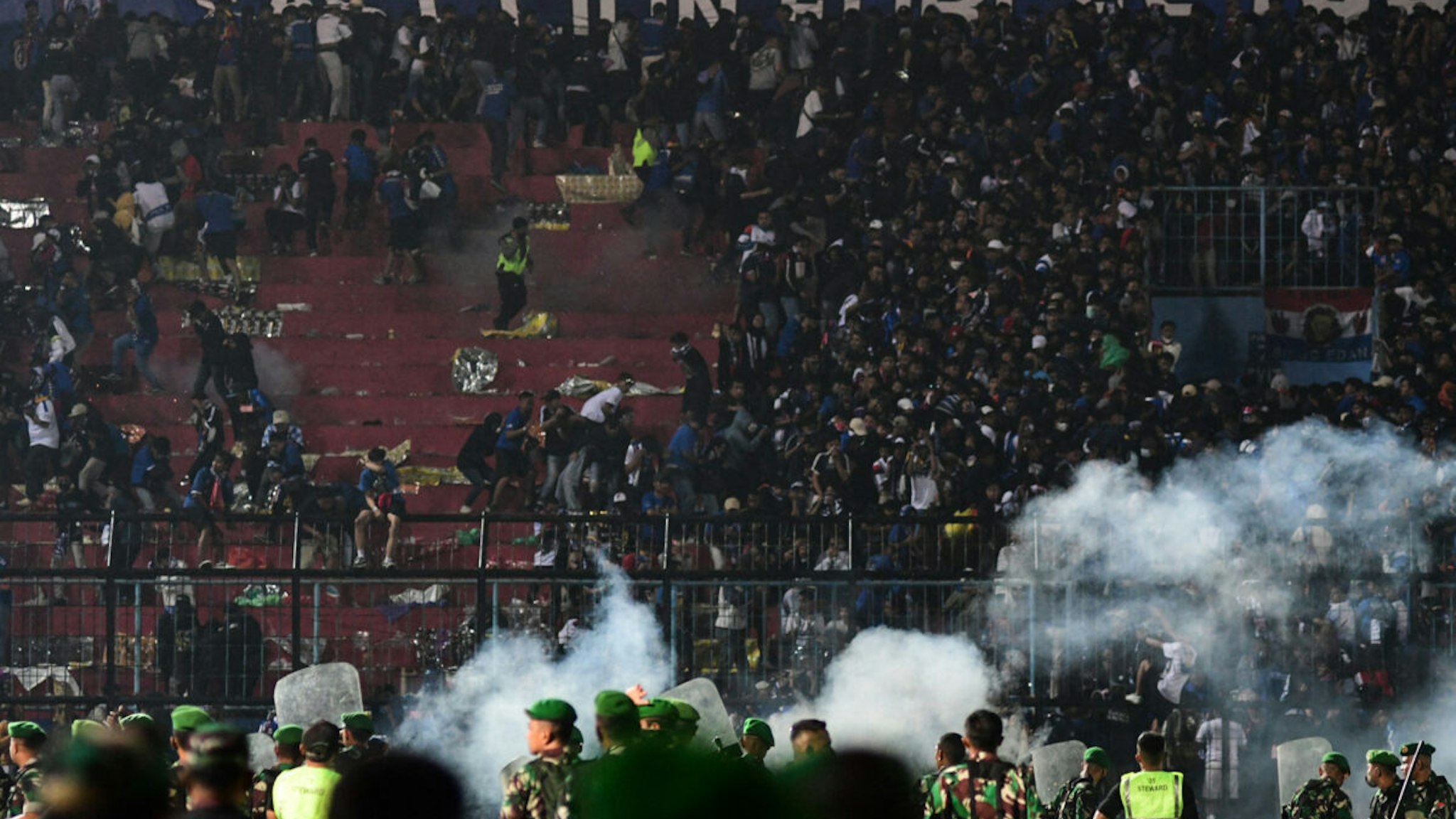 This picture taken on October 1, 2022 shows security personnel (lower) on the pitch after a football match between Arema FC and Persebaya Surabaya at Kanjuruhan stadium in Malang, East Java