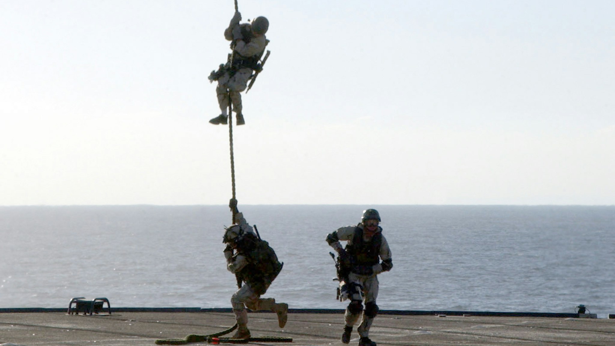A U.S. Navy SEAL (SEa, Air, and Land) rappels from an MH-53 "Pave Low" helicopter to the deck of the amphibious command ship USS Mount Whitney during a training exercise January 17, 2003 while at sea.