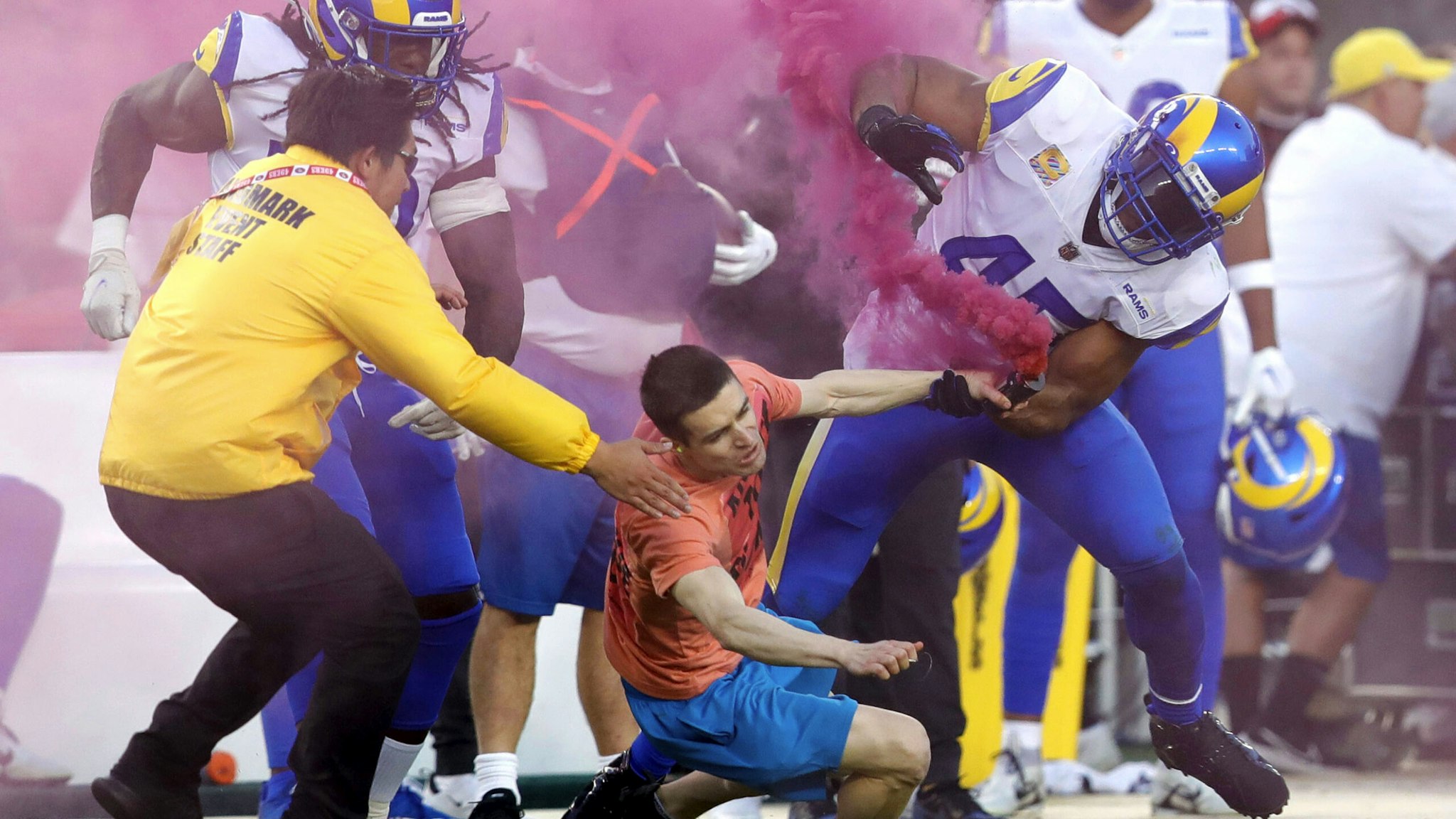 SANTA CLARA, CALIFORNIA - OCTOBER 03: A fan with a smoke bomb is tackled on the field by Los Angeles Rams' Bobby Wagner, #45 Takkarist McKinley #50 and a security guard during their NFL game against the San Francisco 49ers at Levis Stadium in Santa Clara, Calif., on Monday, Oct. 3, 2022.