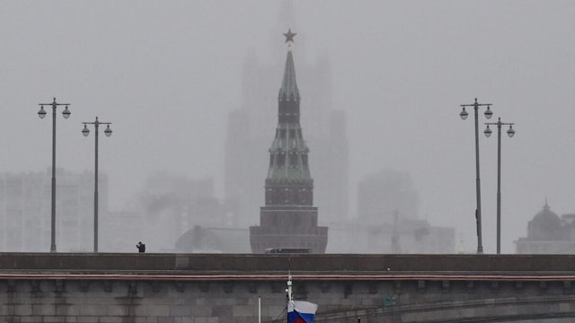 A pedestrian walks along a bridge during the rain over the Moskva River in front of the Vodovzvodnaya tower of the Kremlin and the Russian Foreign Ministry headquarters (background) in central Moscow on October 4, 2022