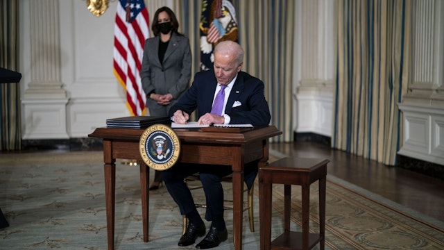 U.S. President Joe Biden signs an executive order in the State Dining Room of the White House in Washington, D.C., U.S., on Tuesday, Jan. 26, 2021. Biden signed a set of executive orders on Tuesday aimed at improving racial equity across American society, including combating discrimination in housing policies and ending the use of private prisons.