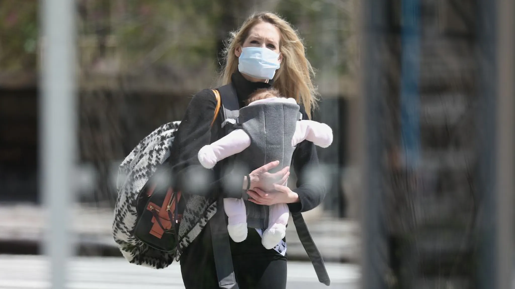 mother with baby A young mother wearing a protective mask holds her baby while walking during the coronavirus pandemic on April 15, 2020 in New York City.