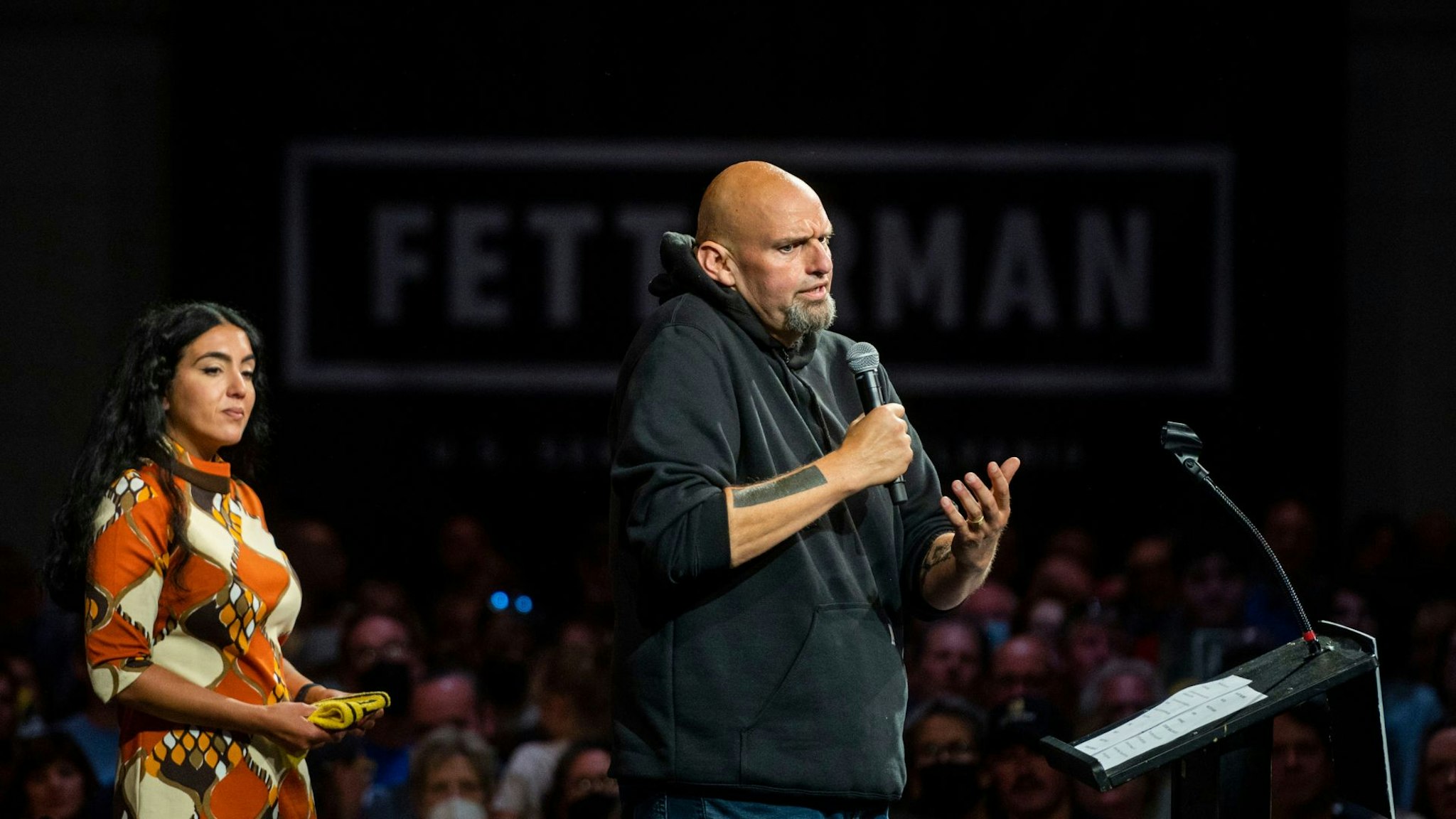 ERIE, PA - AUGUST 12: Democratic Senate candidate Lt. Gov. John Fetterman (D-PA) speaks during a rally as his wife Gisele Barreto Fetterman looks on at the Bayfront Convention Center on August 12, 2022 in Erie, Pennsylvania. Fetterman made his return to the campaign trail in Erie after recovering from a stroke he suffered in May.