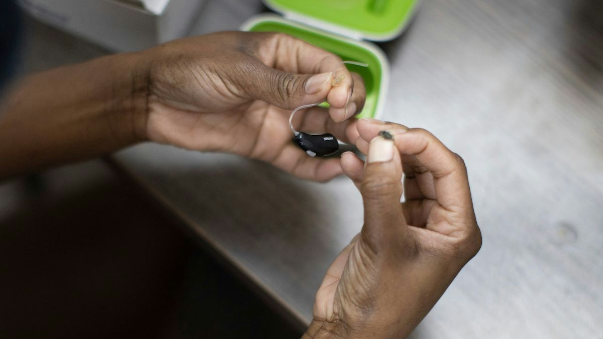 A patient holds her hearing aid as she visits Hear Again America for a checkup on October 20, 2021 in Fort Lauderdale, Florida.