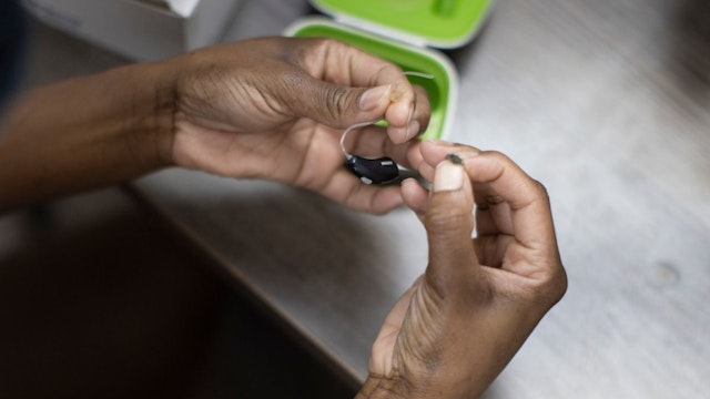 A patient holds her hearing aid as she visits Hear Again America for a checkup on October 20, 2021 in Fort Lauderdale, Florida.
