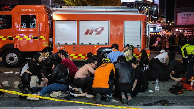 This picture taken on October 30, 2022 shows emergency workers and others assisting people who were caught in a Halloween stampede in the district of Itaewon in Seoul.