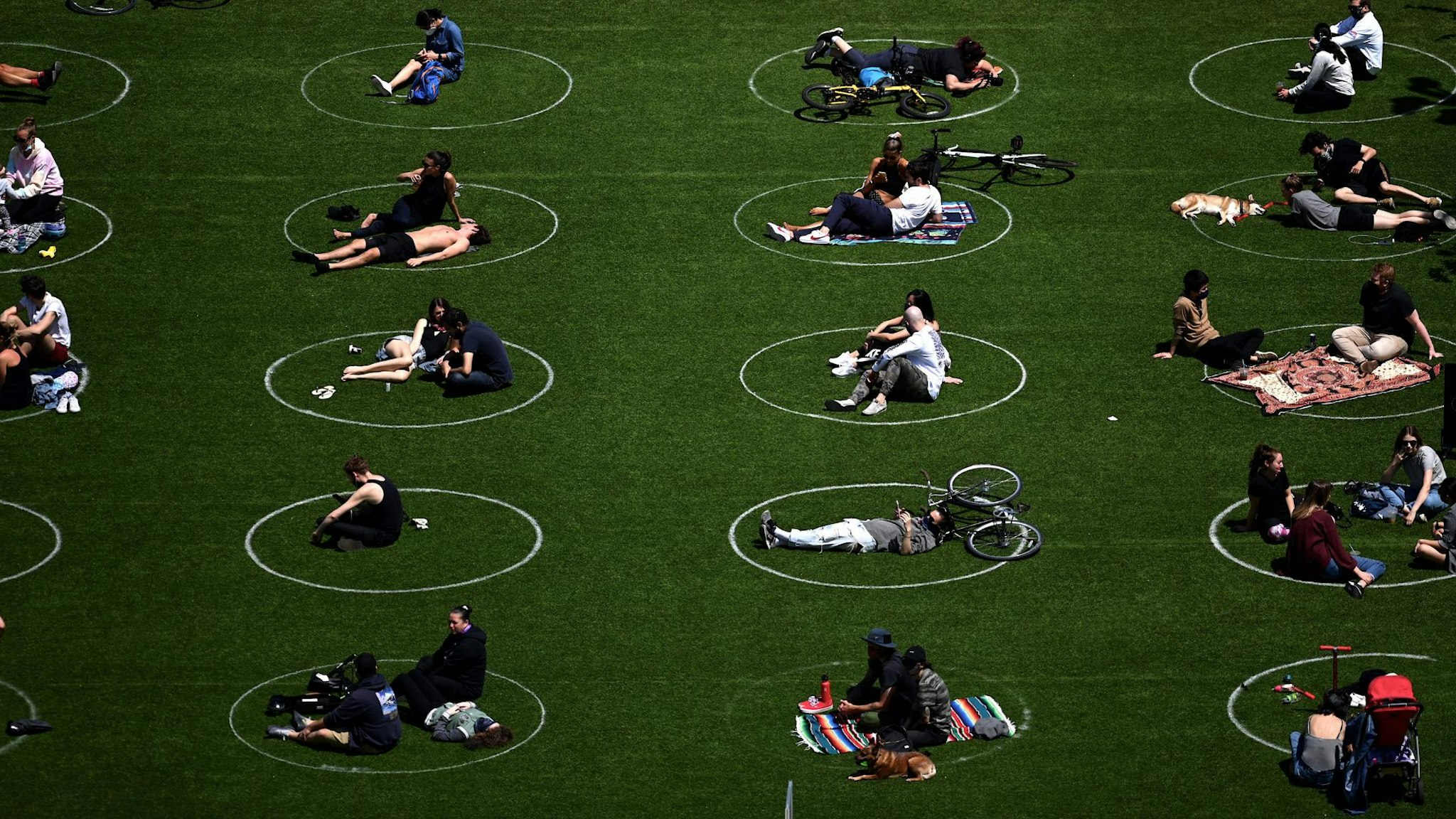 TOPSHOT - People are seen practising social distancing in white circles in Domino Park, during the Covid-19 pandemic on May 17, 2020 the in Brooklyn borough of New York City.