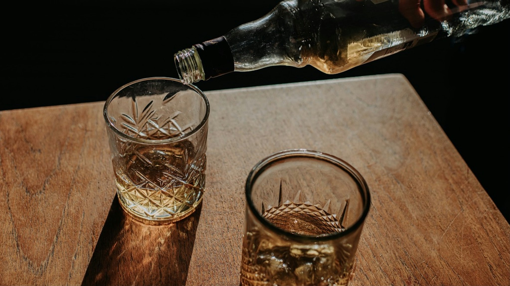 Whisky Pour from a bottle into a cut glass tumbler - stock photo A bottle of whisky is poured into a cut glass tumbler over ice. Space for copy. Catherine Falls Commercial via Getty Images