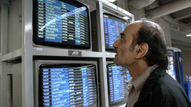 FRANCE-AIRPORT-REFUGEE-SIR ALFRED Mehran Karimi Nasseri checks the monitors 12 August 2004 in the terminal one of Paris Charles De Gaulle airport. Known as "Sir Alfred Mehran", Mehran Karimi Nasseri is a 59 year-old Iranian refugee who has been living in Roissy for 16 years, and whose life has therefore inspired American film director Steven Spielberg for the character of the protagonist in the movie "The Terminal". (Photo by STEPHANE DE SAKUTIN / AFP) (Photo by STEPHANE DE SAKUTIN/AFP via Getty Images) STEPHANE DE SAKUTIN / Contributor