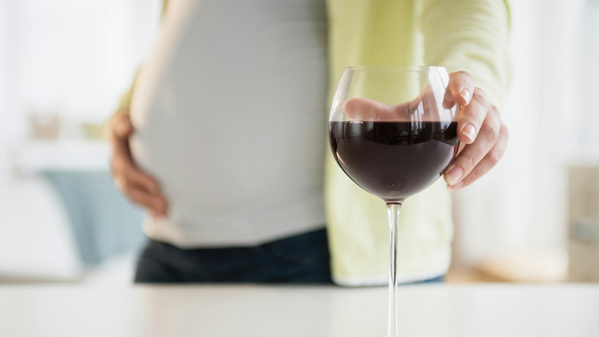 Pregnant woman with glass of red wine - stock photo Jamie Grill via Getty Images