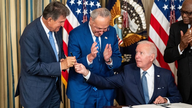WASHINGTON, DC - AUGUST 16: President Joe Biden, center, hands the pen used to sign H.R. 5376, the Inflation Reduction Act of 2022 into law, to Sen. Joe Manchin (D-WV) in the State Dining Room of the White House on Tuesday, Aug. 16, 2022 in Washington, DC. The 737 billion dollar bill focuses on climate change, lowering health care costs and creating clean energy jobs.