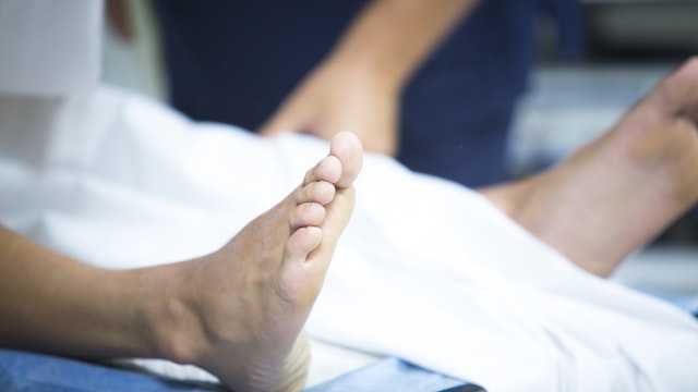 Low Section Of Patient Lying On Hospital Bed - stock photo