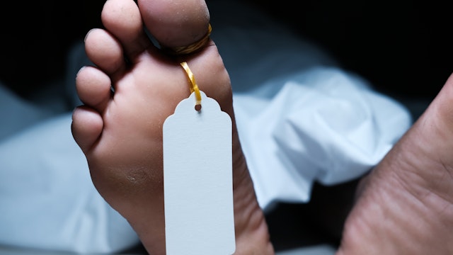 Two feet of a dead body with a tag attached to the toe - stock photo