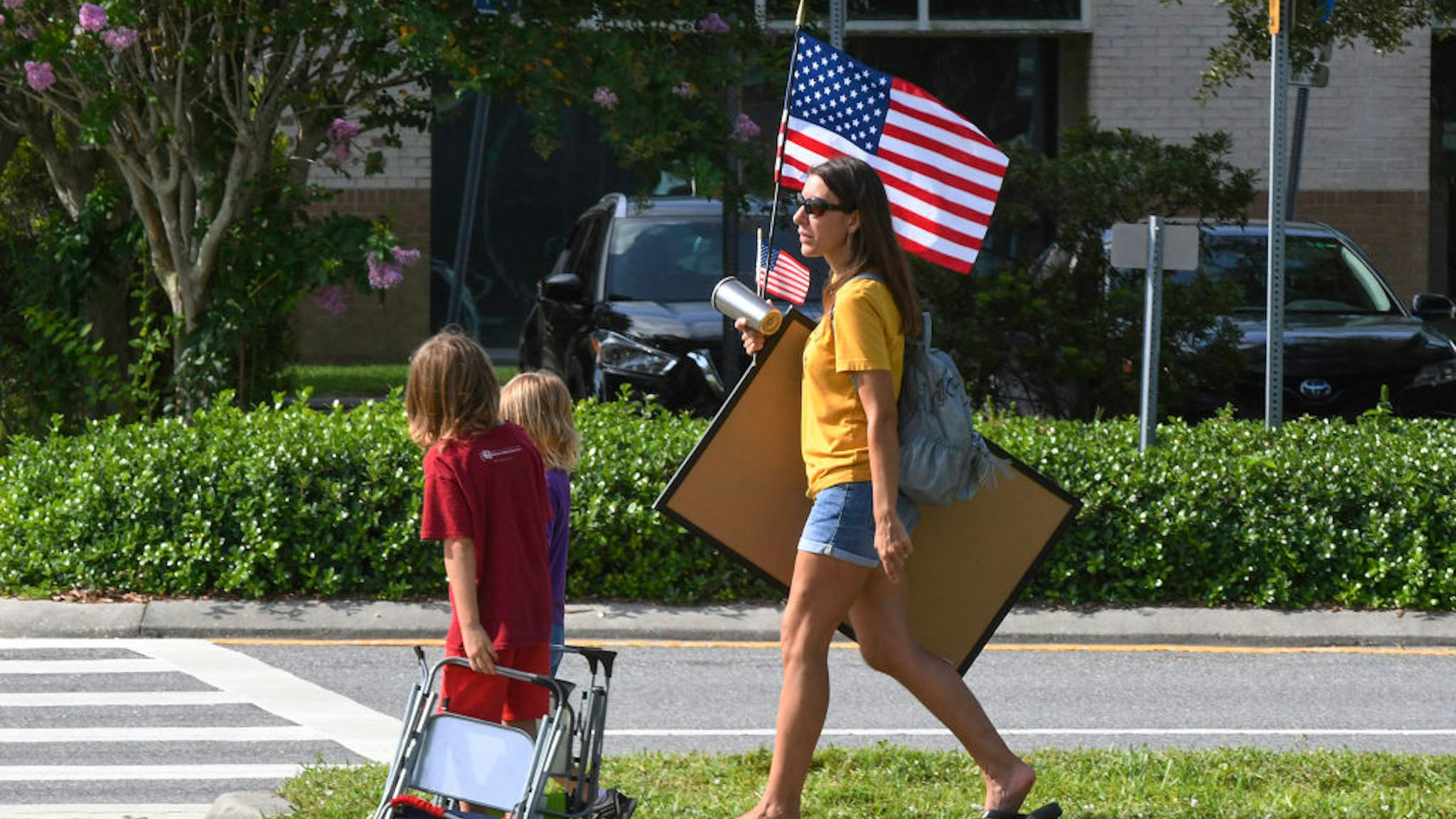 VIERA, FLORIDA, UNITED STATES - 2021/08/30: A mother holding an American flag arrives with her children to demonstrate outside an emergency meeting of the Brevard County, Florida School Board in Viera to discuss whether face masks in local schools should be mandatory. An executive order signed by Florida Governor Ron DeSantis banning mask mandates in schools was thrown out by a Florida judge on Friday. (Photo by Paul Hennessy/SOPA Images/LightRocket via Getty Images)