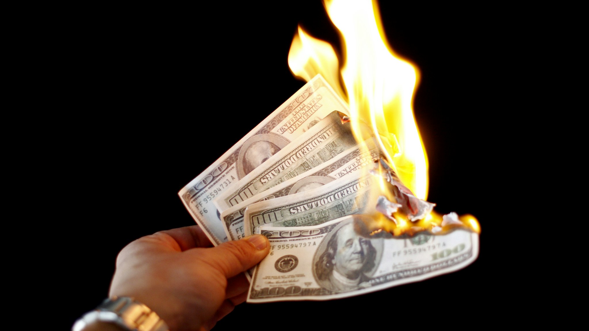 Hundred dollar bills on fire/Getty Images