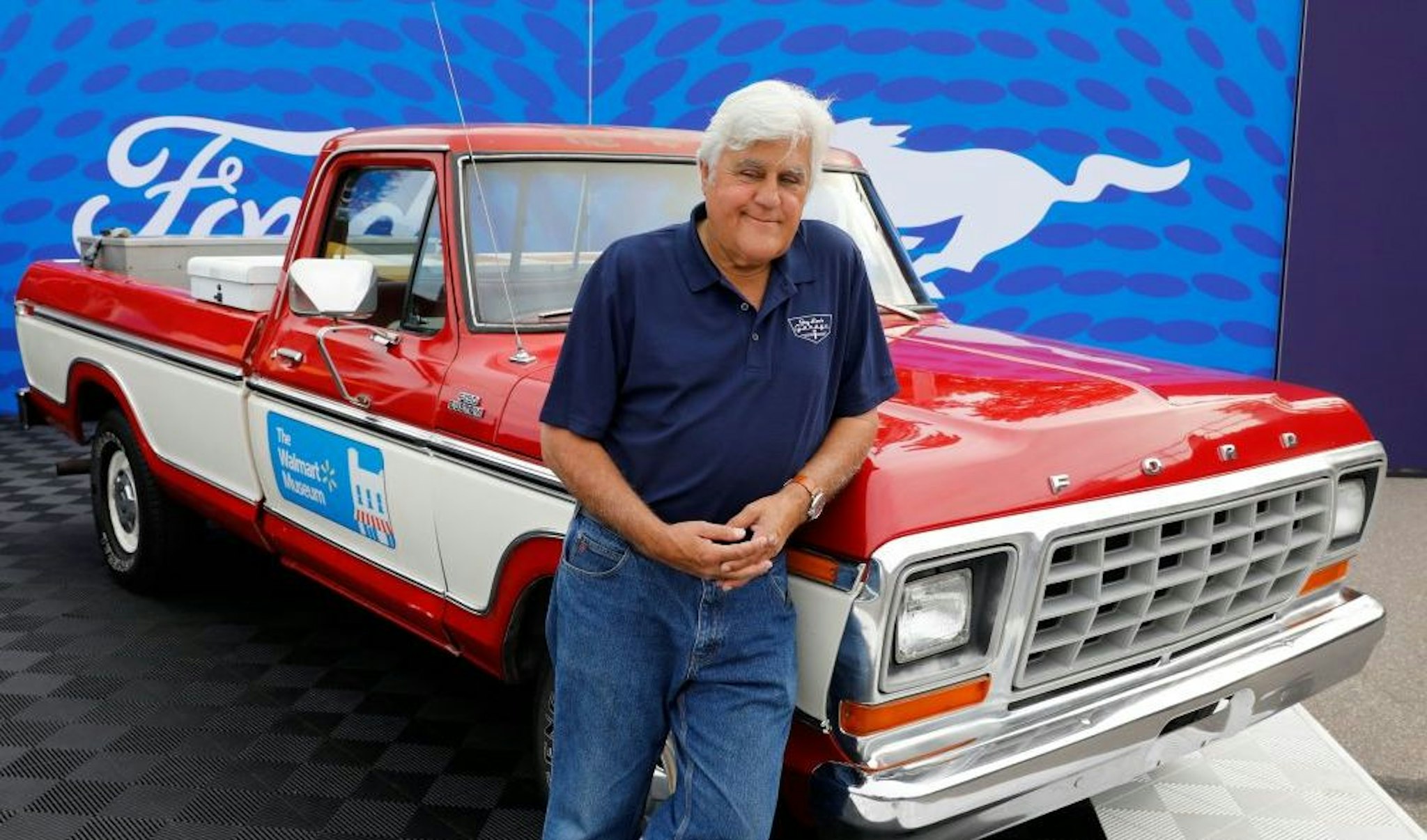 US comedian Jay Leno poses in front of a 1979 Ford F-150 pickup, in the style of one owned by Walmart founder Sam Walton, on August 20, 2022, during the 27th annual Woodward Dream Cruise, in Royal Oak, Michigan. - The event is a celebration of automotive culture, attracting nearly one-million visitors and thousands of classic vehicles.