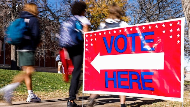 Students walk past a voting sign outside a polling location at Denver East High School on November 8, 2022 in Denver, Colorado.