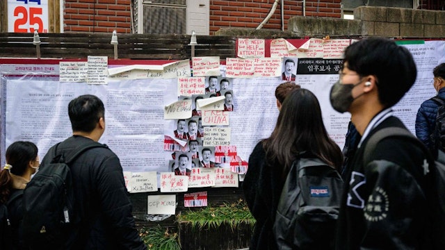 Students and pedestrians stop to look at anti-Chinese government posters displayed outside a university in Seoul on November 28, 2022, following protests over China's zero-Covid policy on the streets of some of its biggest cities calling for an end to lockdowns and greater political freedoms.