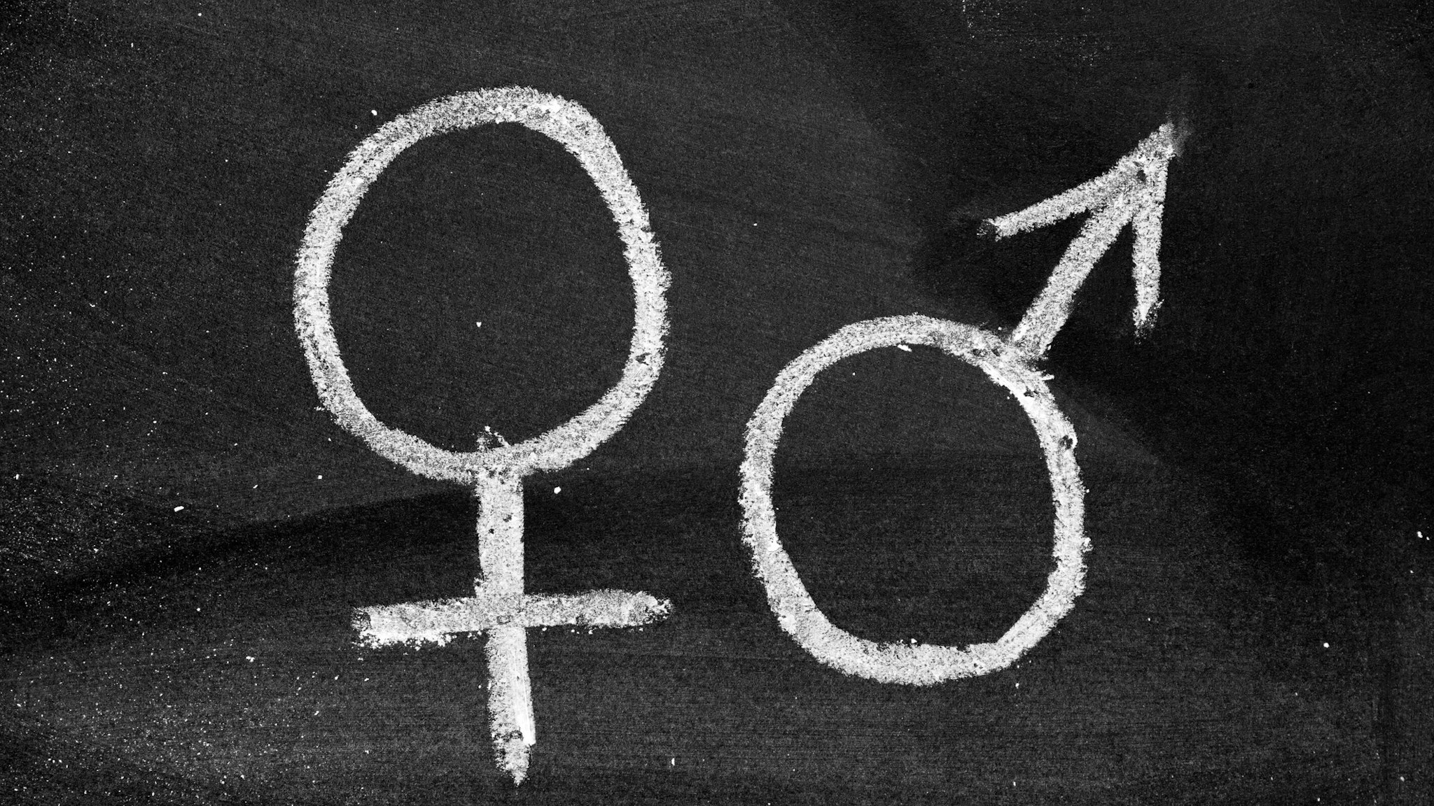 Male and female gender symbols on blackboard - stock photo akinbostanci via Getty Images