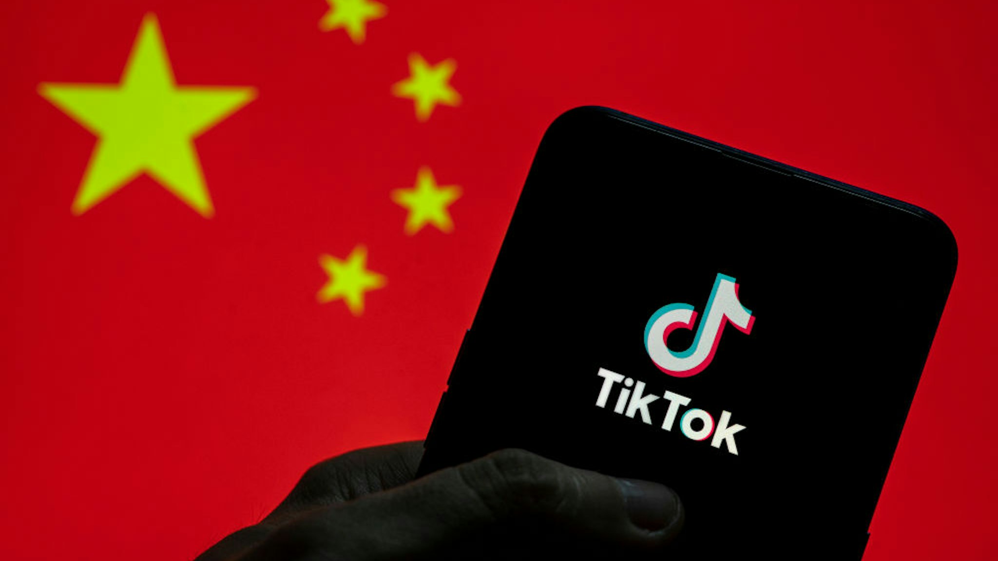 CHINA - 2021/03/28: In this photo illustration the Chinese video-sharing social networking service company TikTok logo seen on an Android mobile device with People's Republic of China flag in the background. (Photo Illustration by