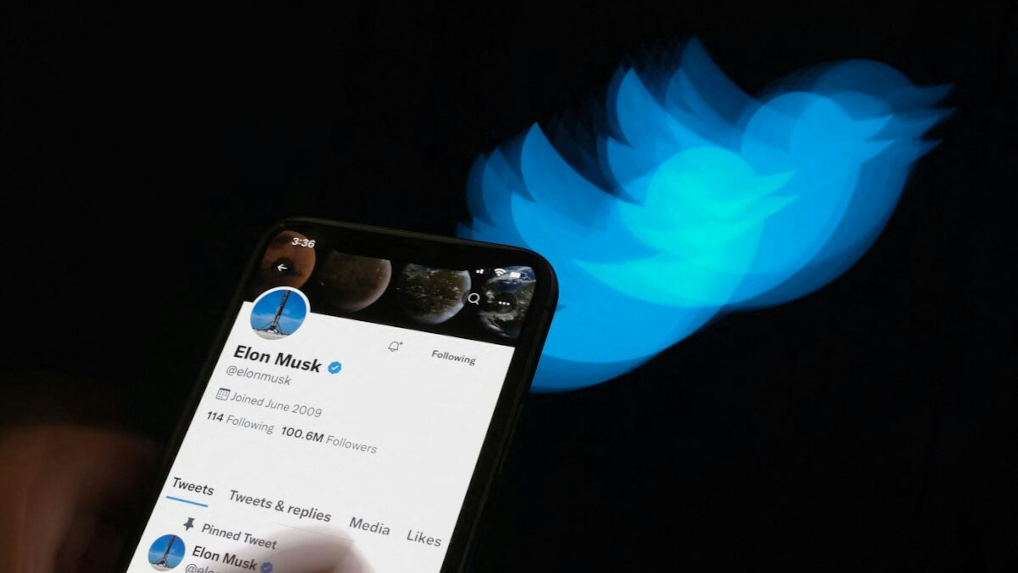 This illustration photo taken on July 8, 2022 shows Elon Musk's Twitter page displayed on the screen of a smartphone with Twitter logo in the background in Los Angeles. - Elon Musk pulled the plug on his deal to buy Twitter on July 8, 2022, accusing the company of "misleading" statements about the number of fake accounts, a regulatory filing showed.