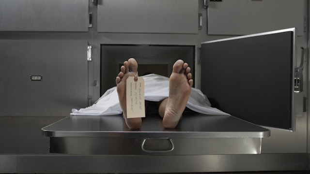 Cadaver on autopsy table, label tied to toe - stock photo