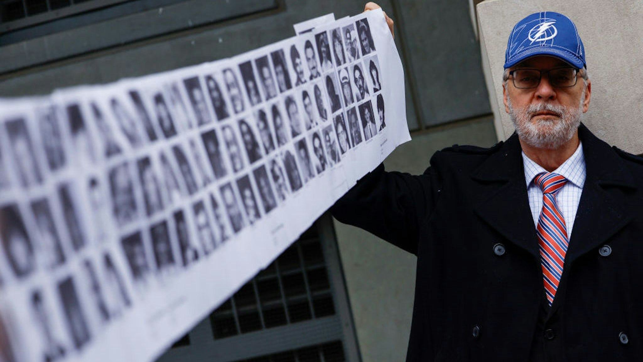 WASHINGTON, DC - DECEMBER 12: Paul Hudson, whose daughter Melina was one of the victims in the Pan Am Flight 103 Lockerbie bombing, holds up a banner of pictures of additional victims outside the federal court before the trial for a Libyan man accused of making the bomb that exploded the plane on December 12, 2022 in Washington, DC. U.S. officials announced that they had arrested Abu Agila Mohammad Mas’ud Kheir Al-Marimi for his involvement in the bombing that killed 270 people in December 1988. (Photo by Anna Moneymaker/Getty Images)