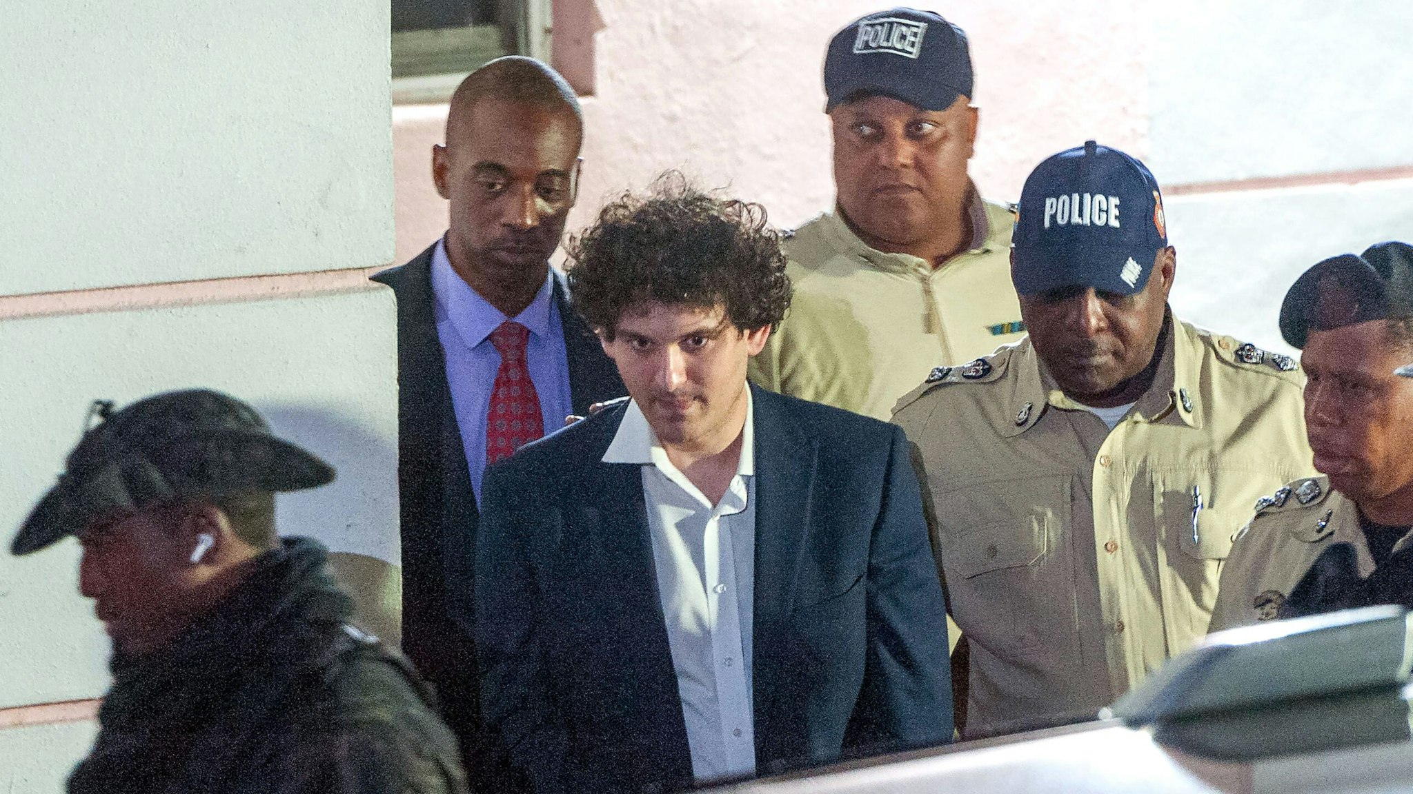 TOPSHOT - FTX founder Sam Bankman-Fried (C) is led away handcuffed by officers of the Royal Bahamas Police Force in Nassau, Bahamas on December 13, 2022. - Disgraced cryptocurrency tycoon Sam Bankman-Fried was hit with multiple criminal charges December 13, 2022, accused of committing one of the biggest financial frauds in US history. Bankman-Fried will serve time at The Bahamas Department of Corrections until February 8, 2023.