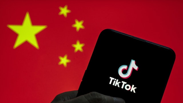 CHINA - 2021/03/28: In this photo illustration the Chinese video-sharing social networking service company TikTok logo seen on an Android mobile device with People's Republic of China flag in the background.